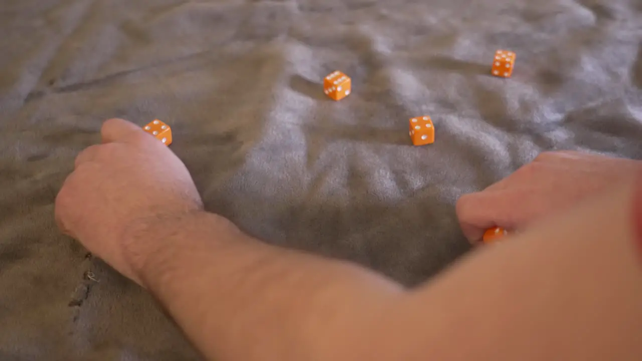 Ten orange dice being rolled in slow motion onto a gray felt platform cover