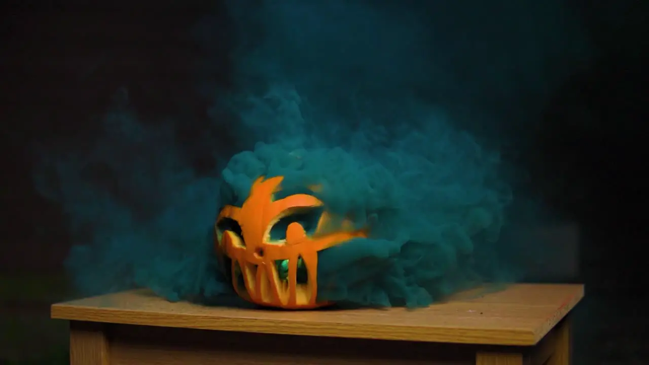 Super thick colourful vivid dark blue smoke coming out of the carved pumpkin in slow-motion