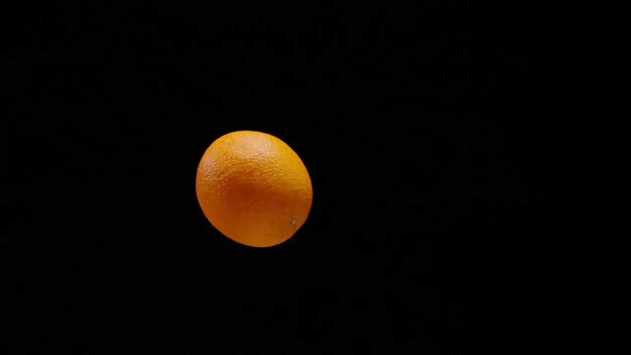 Fresh delicious orange falling down in slow motion isolated black background