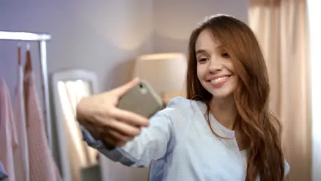 Young woman taking selfie on mobile phone at home Happy woman making selfie