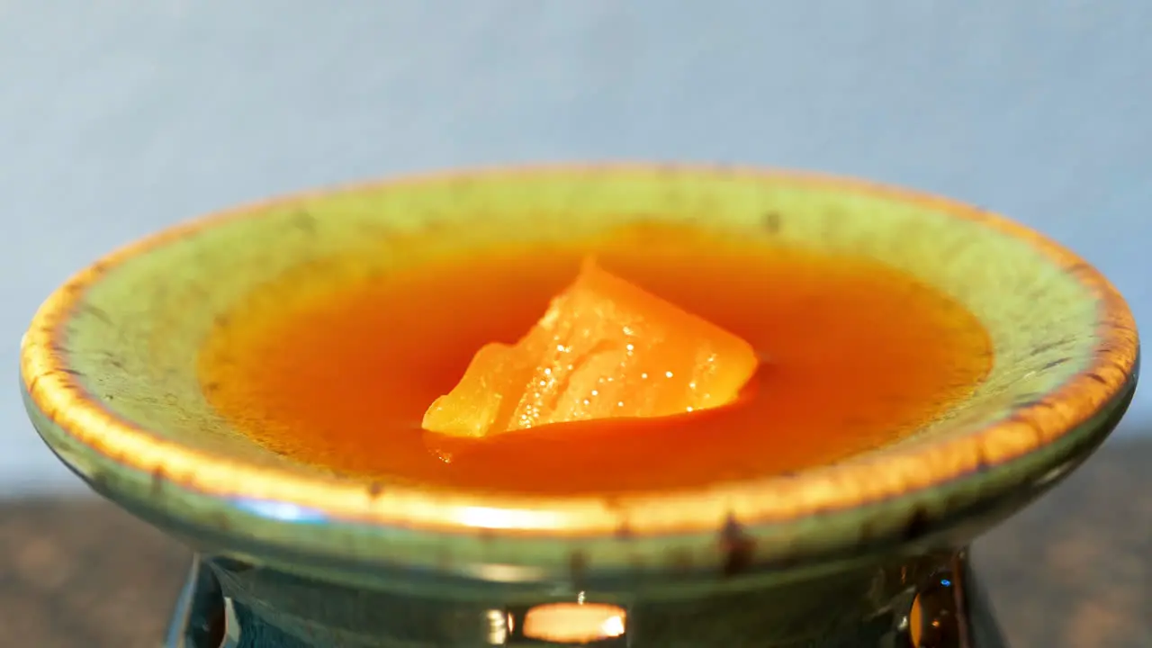 Time lapse of aromatic wax melting over flame-heated bowl concept tranquility fragrance comfort aroma therapy relaxation