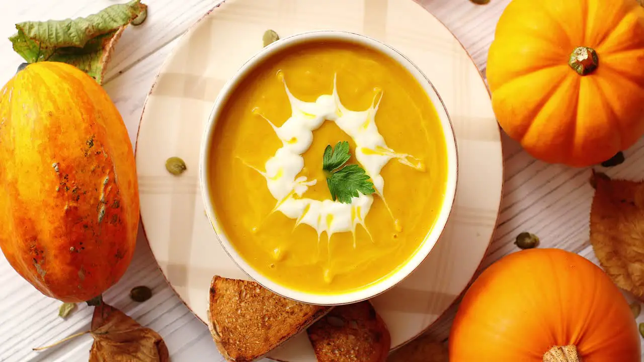 Creamy pumpkin soup in bowl with herb