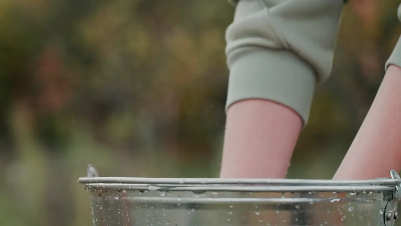 Woman holding several ripe oranges over a bucket of water