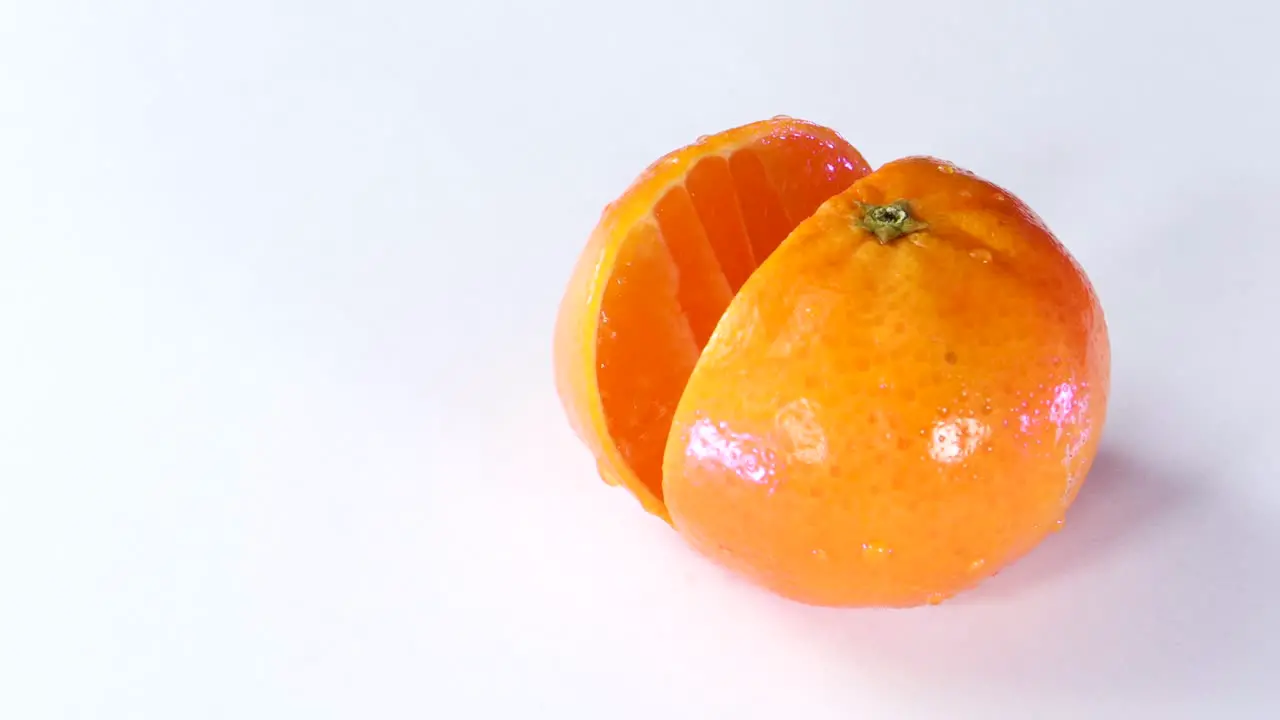 Very sharp knife cutting a thic slice of tangerine in white surface