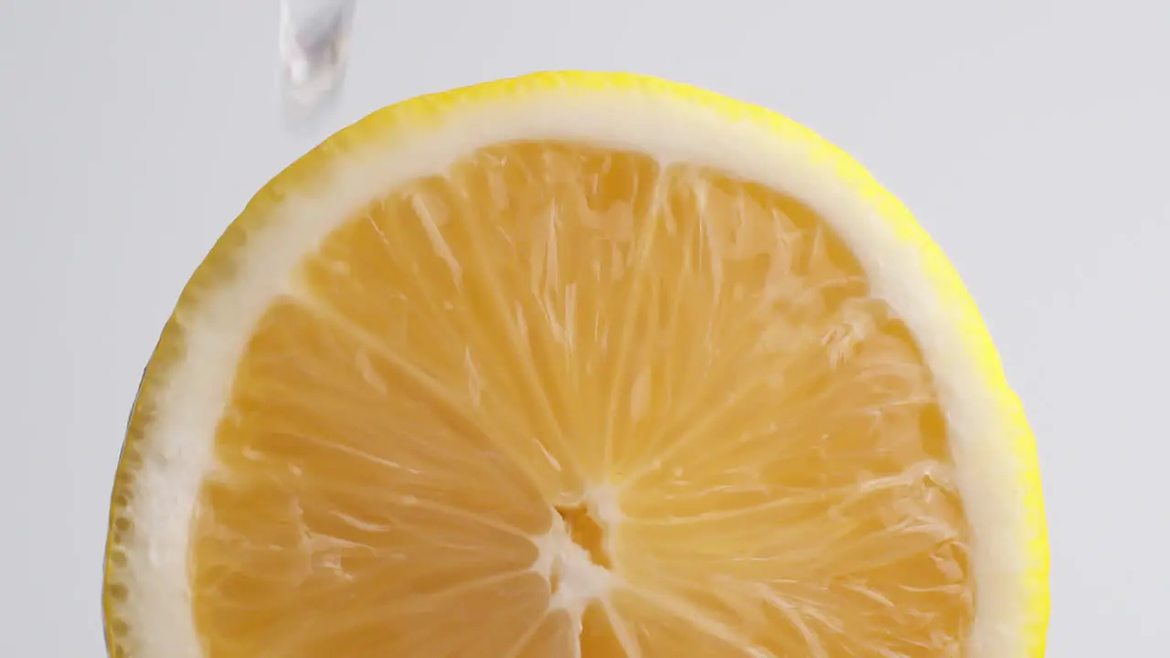 Detail of cut Sicilian lemon with drops of water falling on the piece in slow motion