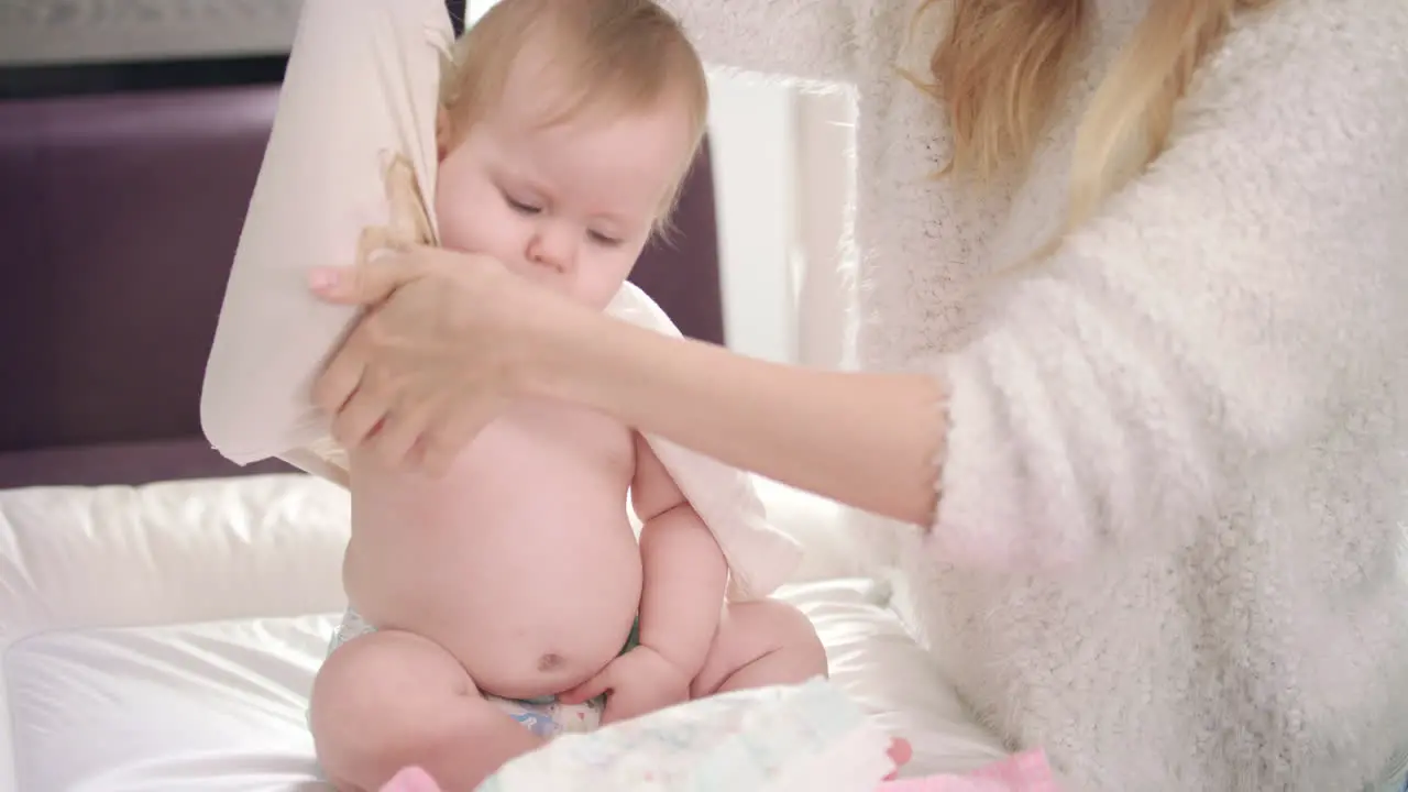 Mom undressing baby Infant going for a walk Baby unclothing on bed