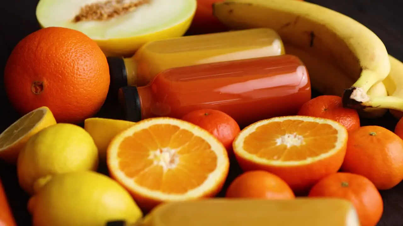 Mix of orange and yellow colored fruits and juices on black wooden background