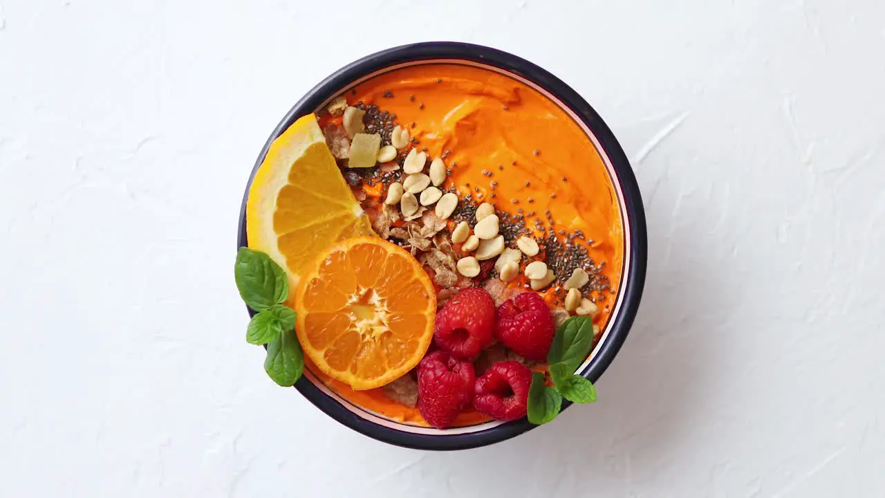 Bowl with fresh healthy smoothie or yogurt With orange slices tangerine raspberry chia and nuts