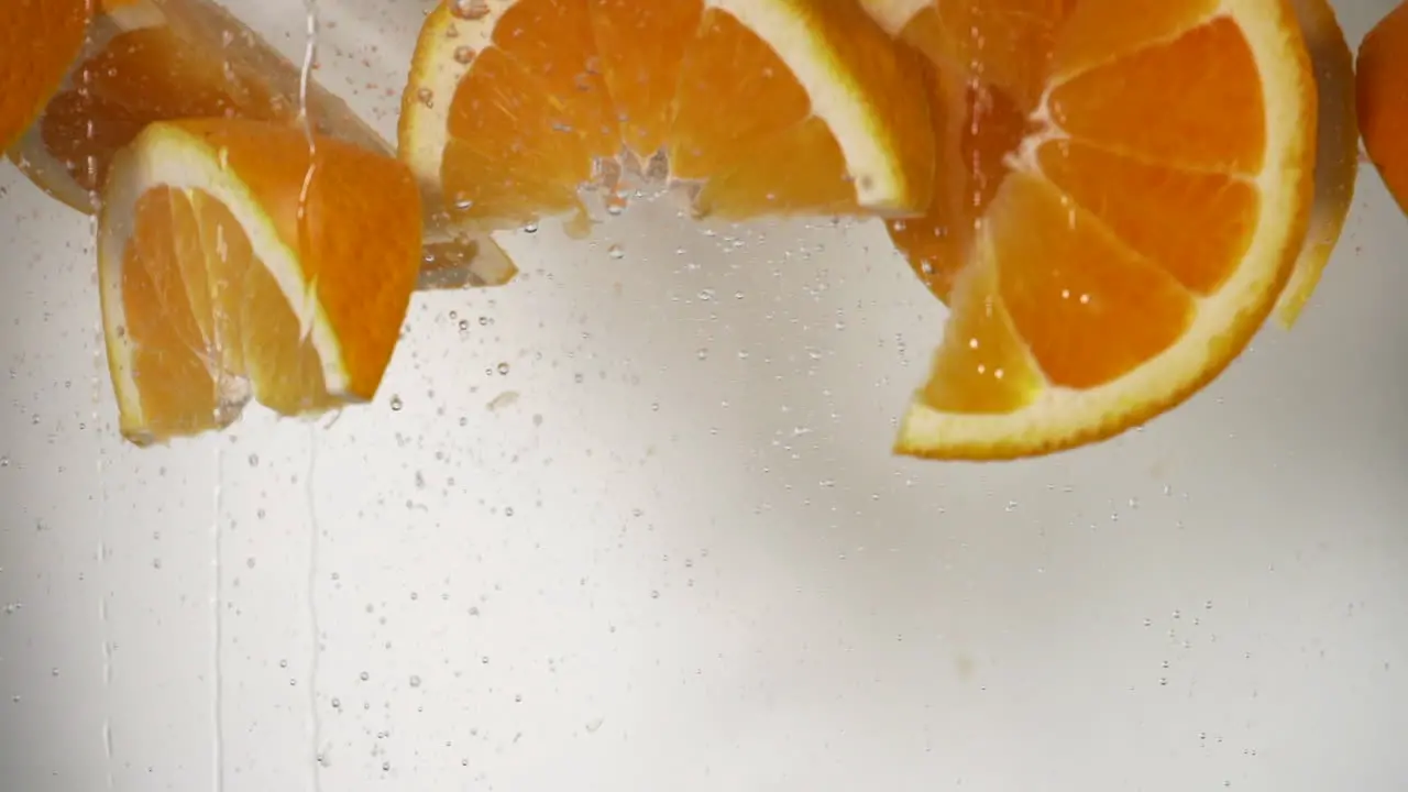 slow motion orange wedges dropping in water refreshing orange falling in water white background