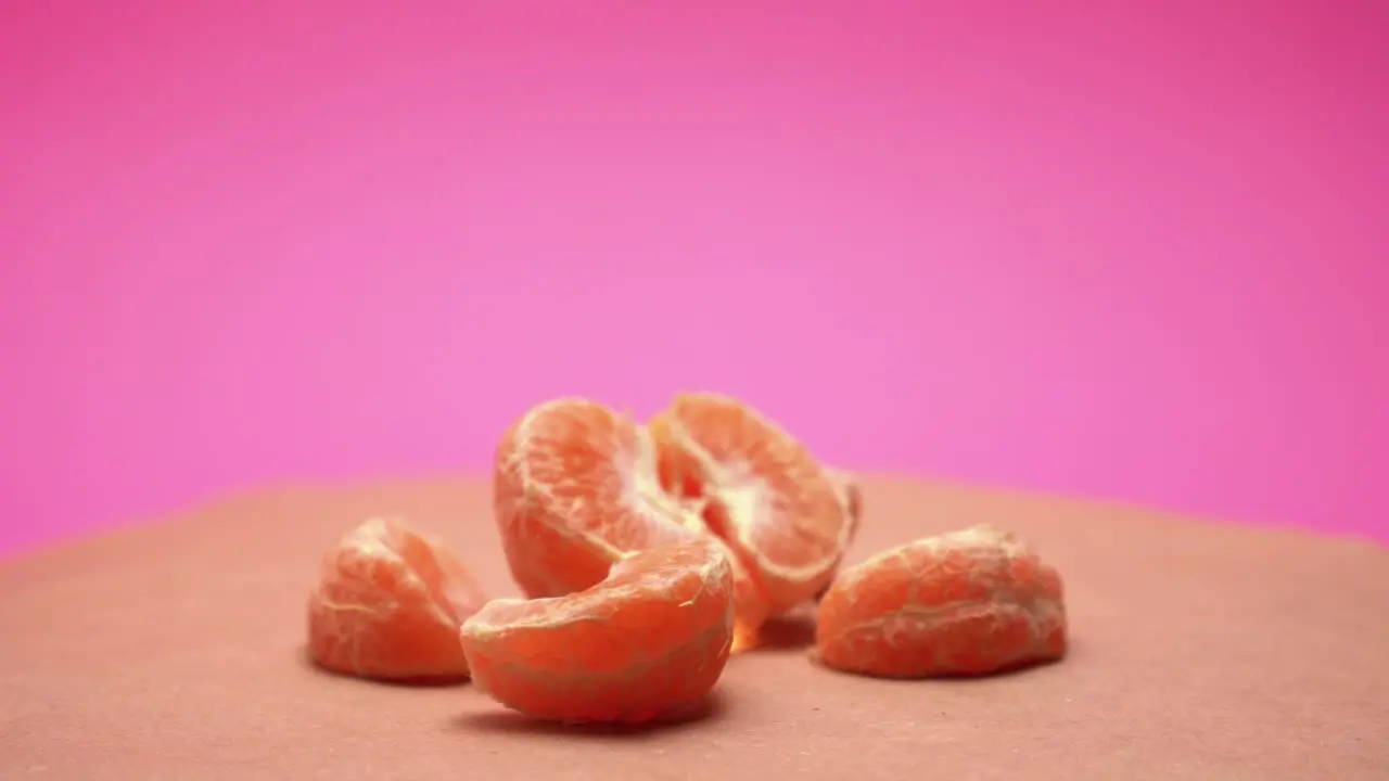 Ripe peeled mandarin rotate on pink and old paper background 4k video with color correction