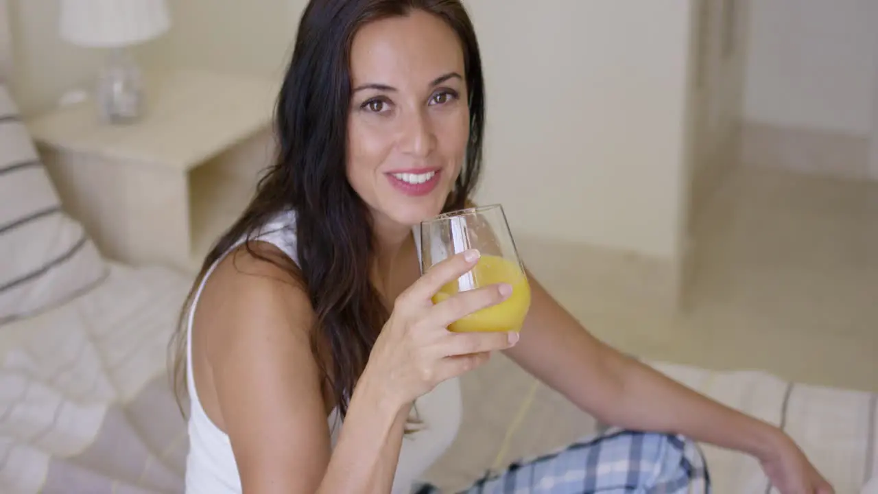 Smiling healthy young woman drinking orange juice