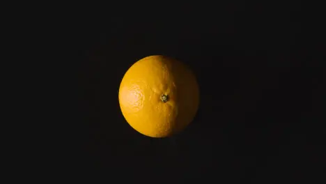 Overhead Studio Shot Of Orange Revolving Against Black Background