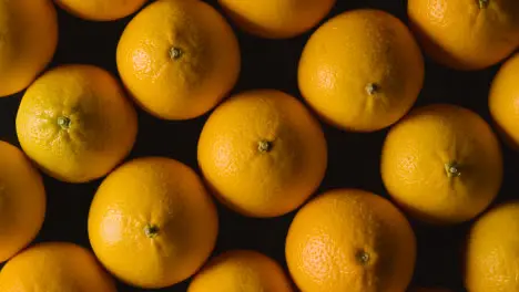 Overhead Studio Shot Of Oranges Being Sprayed With Water Revolving Against Black Background