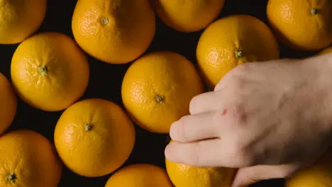 Overhead Studio Shot Of Hand Replacing Orange Onto Revolving Black Background 