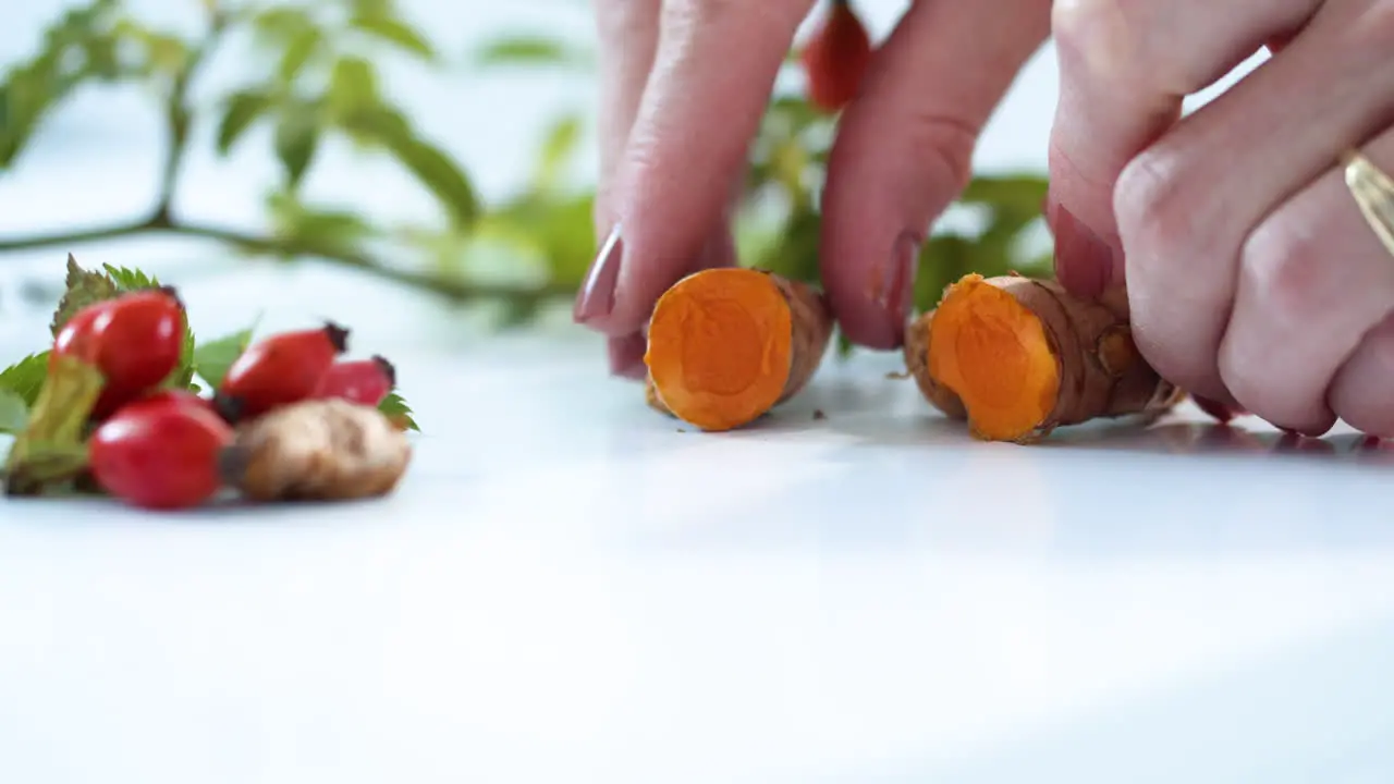 Close up woman's hands opening up turmeric root on kitchen table