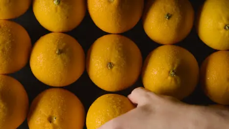 Overhead Studio Shot Of Hand Choosing From Oranges Revolving Against Black Background 1