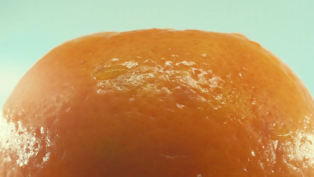 A macro shot of a clementine orange fruit on a rotating 360 stand studio lighting slow motion 4K video