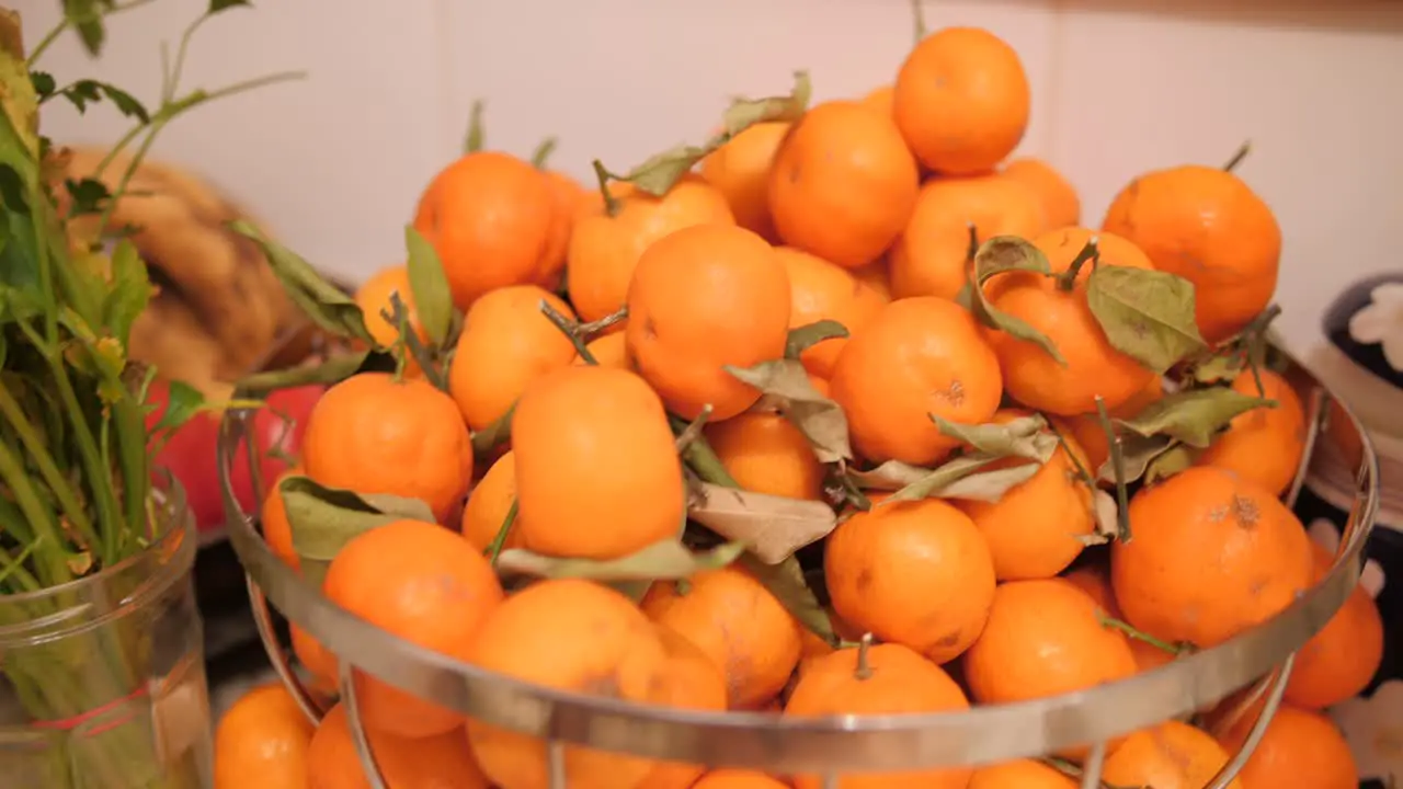 Close up view of metal bowl with ripe orange tangerines a source of vitamin c on a table in the kitchen