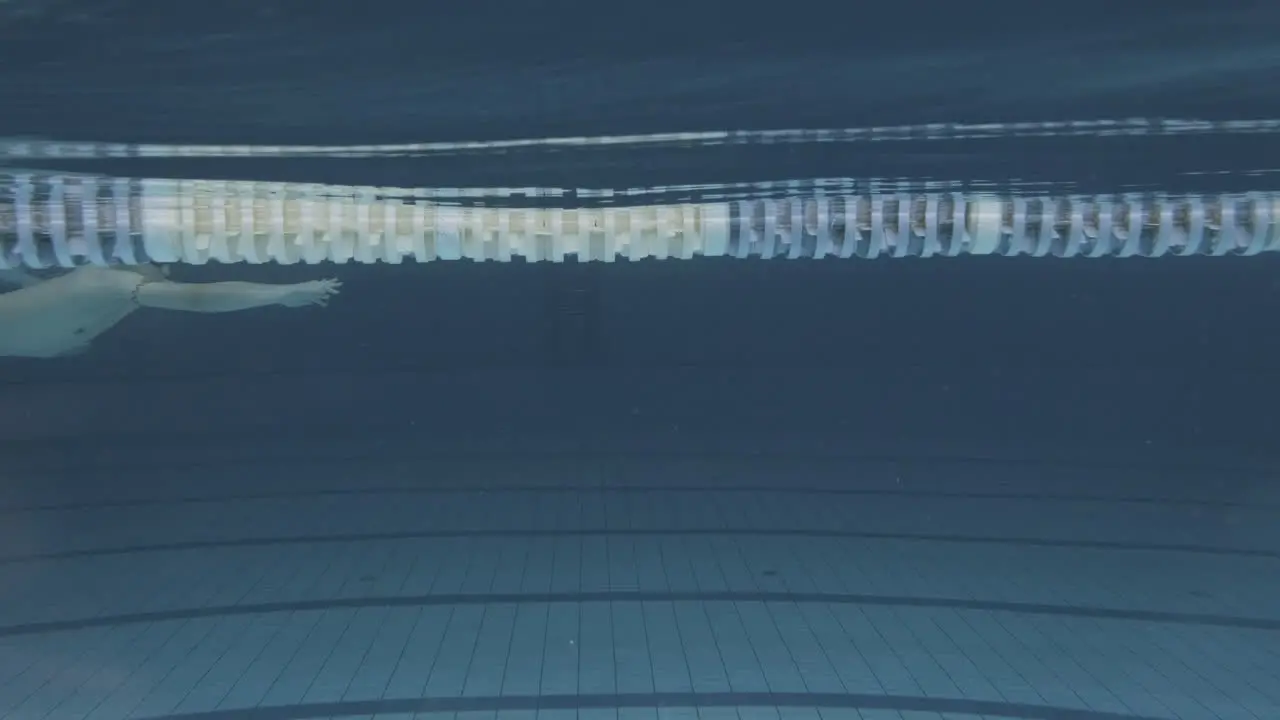 Underwater Side Shot Of Young Female Swimmer With Swimming Cap And Goggles In The Indoor Pool