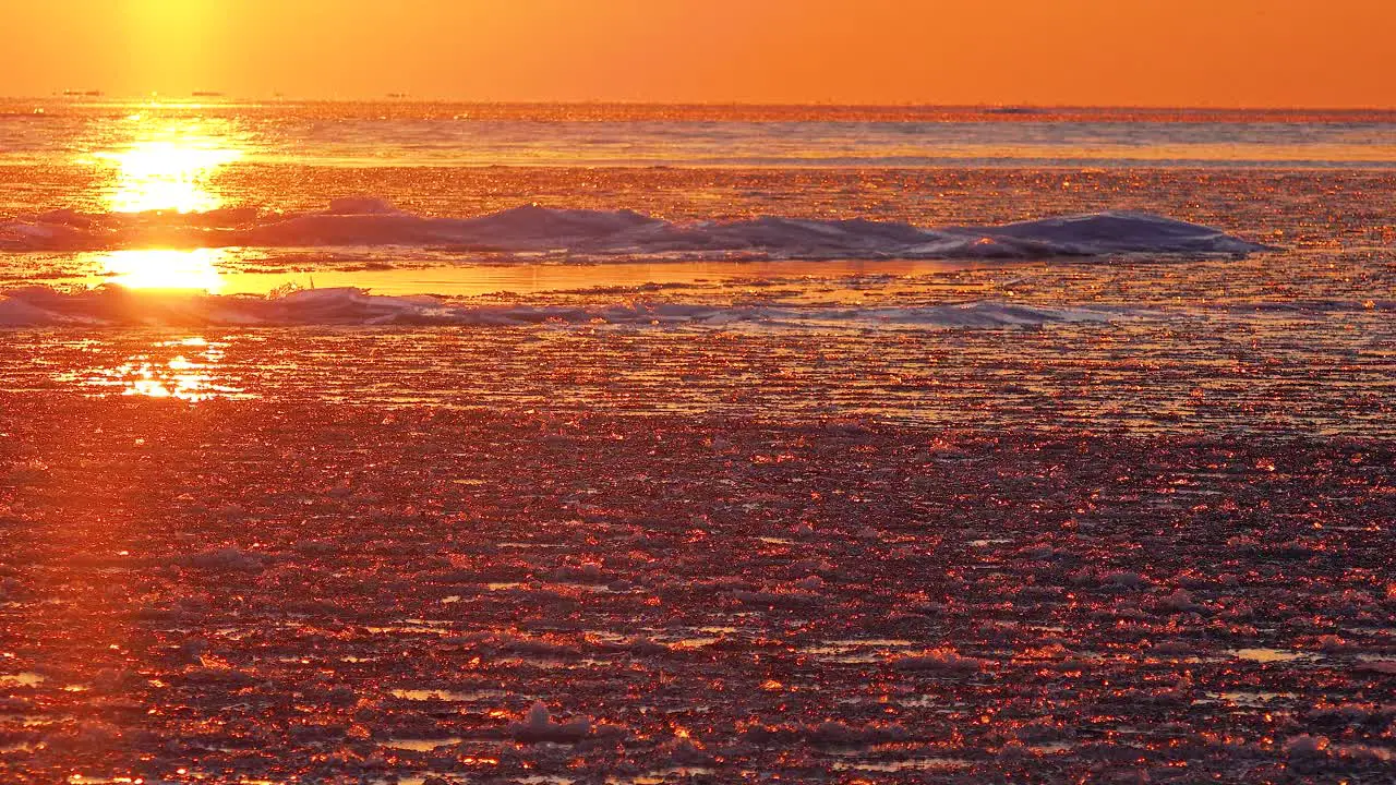 Bright Orange Sunrise Over Ice Covered Water In Winter