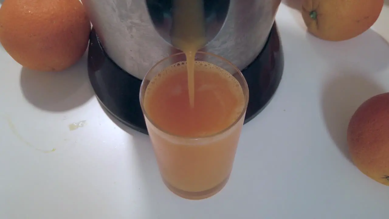 Orange juice pouring in glass on white table