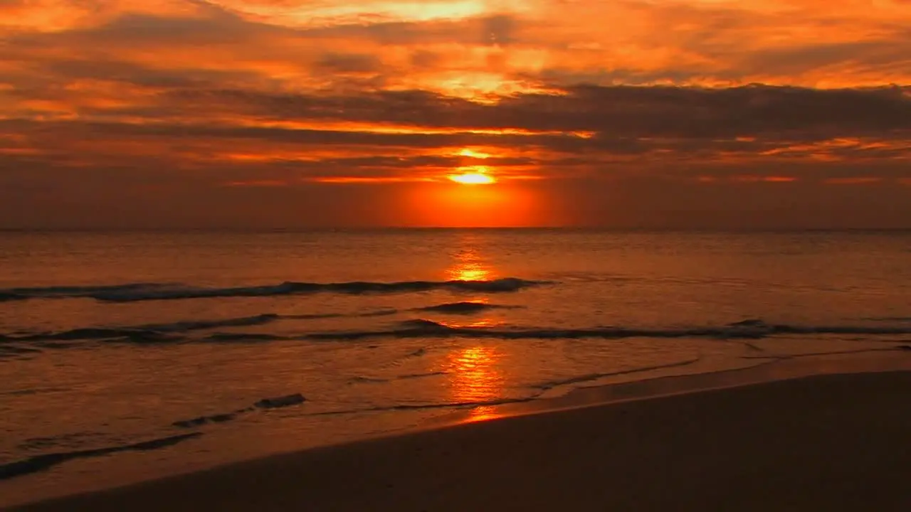 Beach waves slowly break during sunset