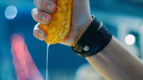 Barman squeezing orange into glass during preparation of cocktail