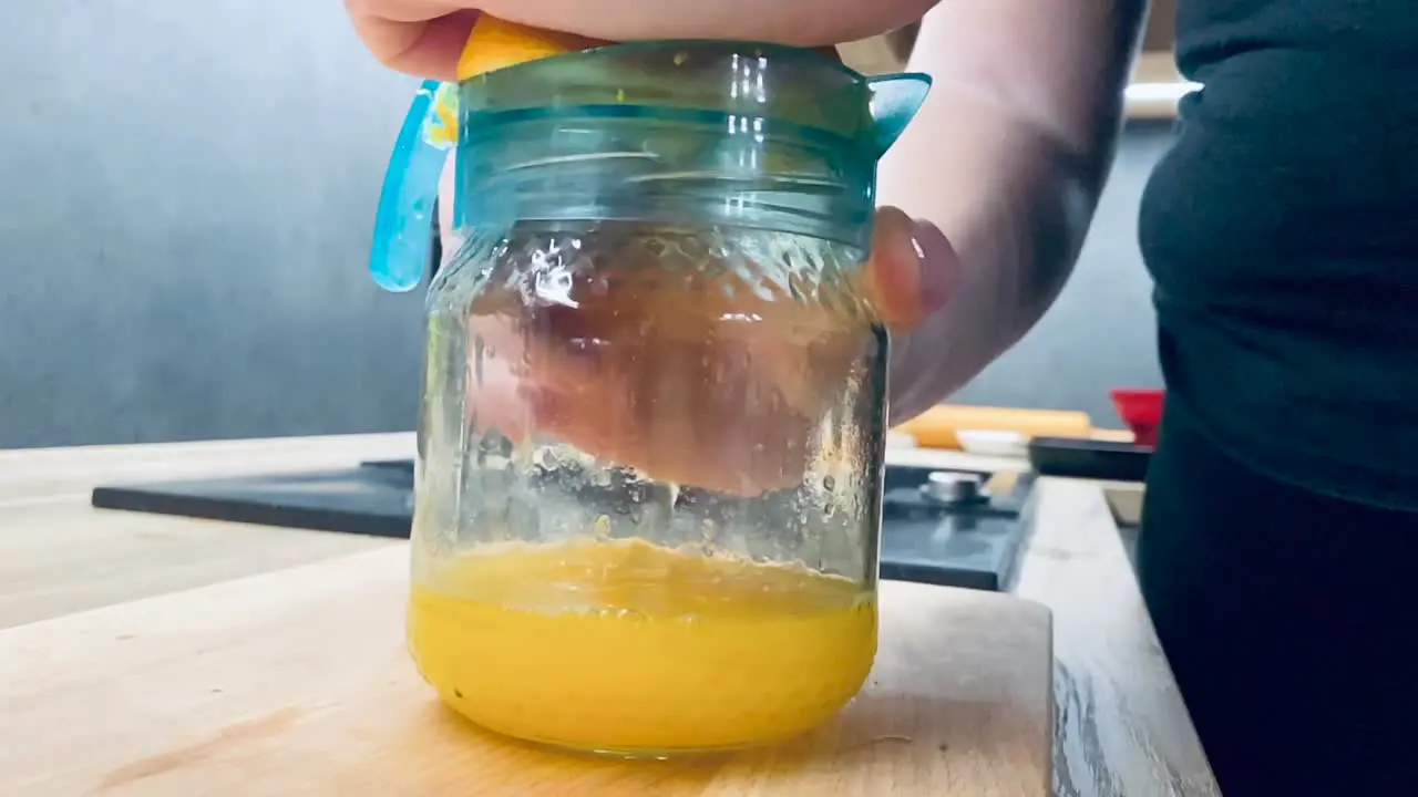 Juicing fresh orange for healthy juice on kitchen counter from side shot in slow motion