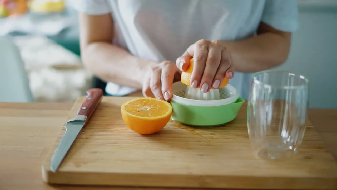 Woman hands squeezing fresh orange juice with citrus squeezer