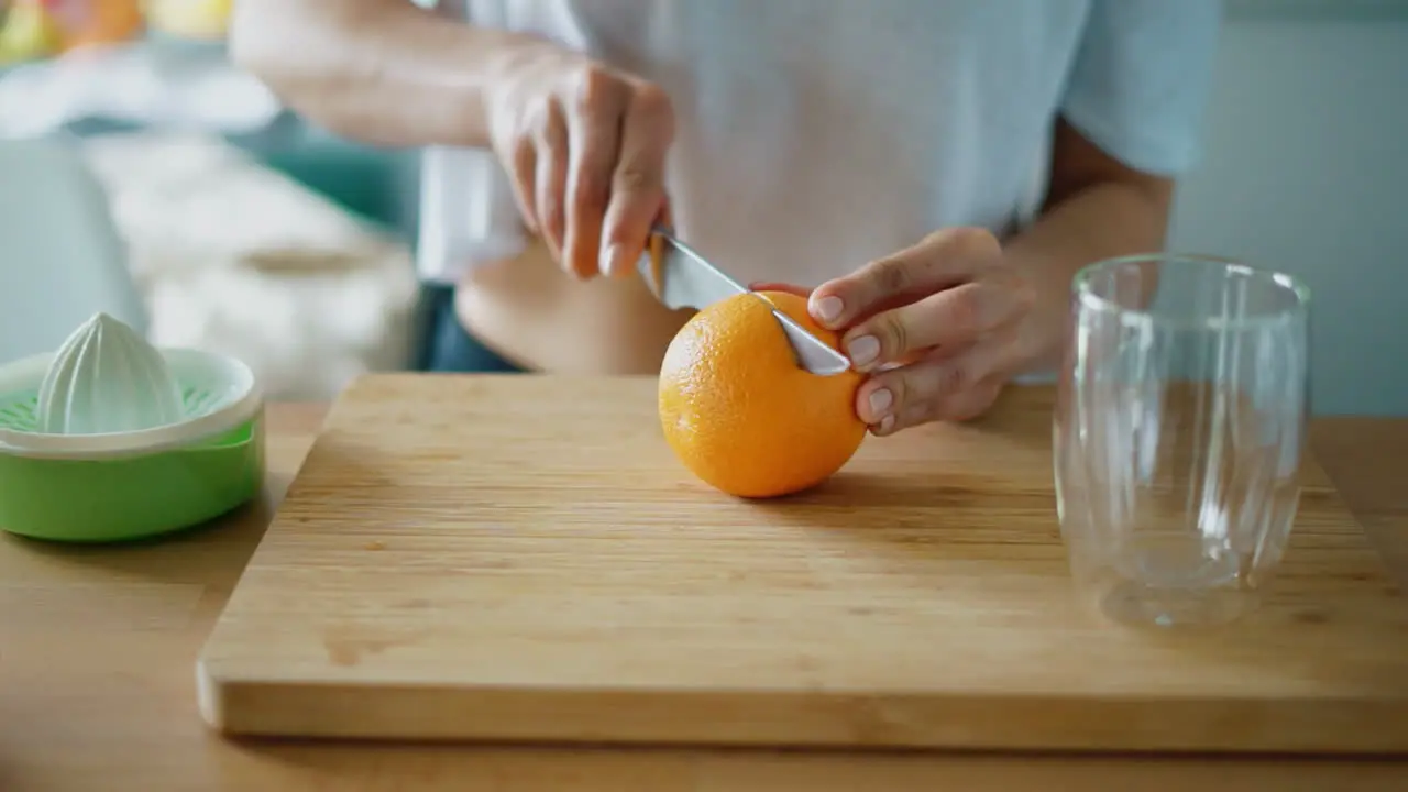 Cutting orange fruit for squeezing fresh juice Close up female hands