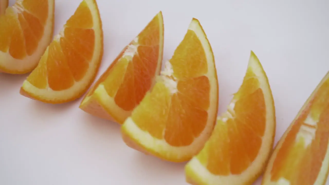 moving shot of orange slices-wedges on white isolated background healthy food choices