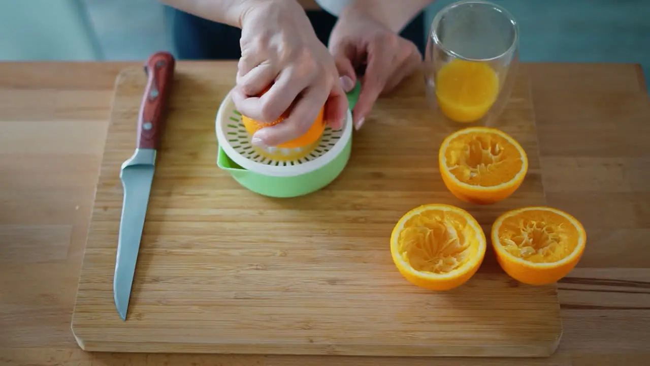 Woman hands making natural orange juice on wooden board