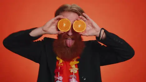 Handsome tourist man putting half of oranges on eyes vegetarian lifestyle vitamins for health