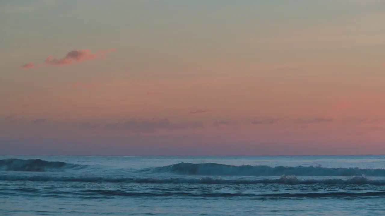 A cloudy burnt orange sunset on the beach with rolling waves and serene feel