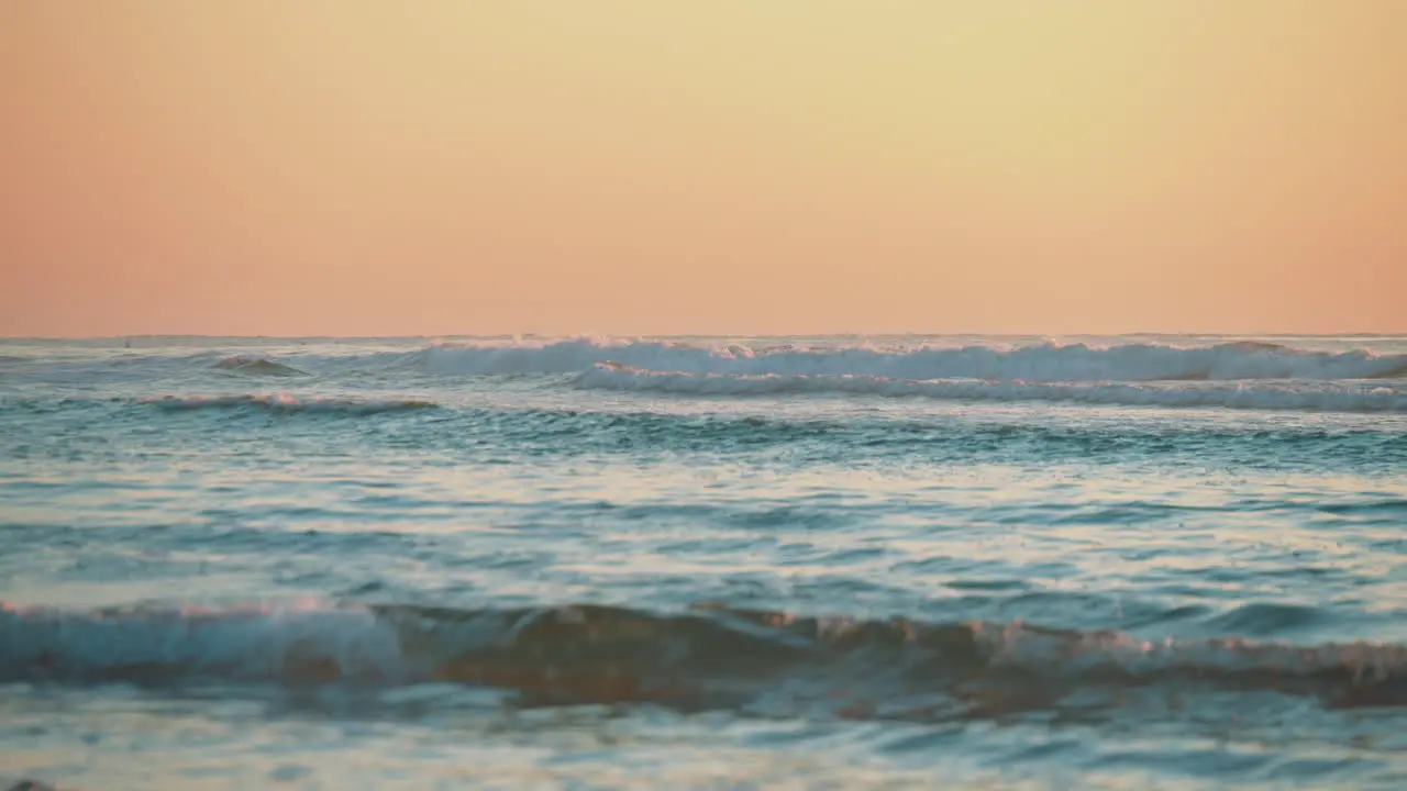 Waves rolling in on the beach with a warming fiery orange sunset