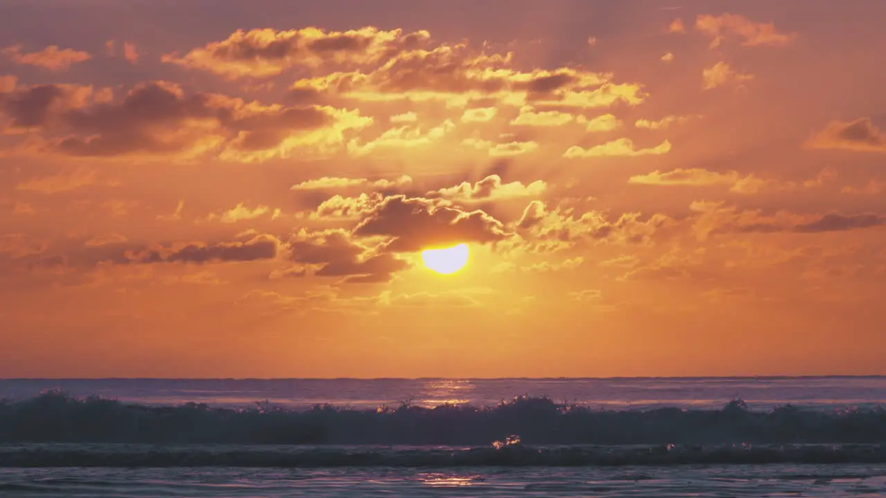 Stunning warming orange beach sunset with dark waves rolling into shore