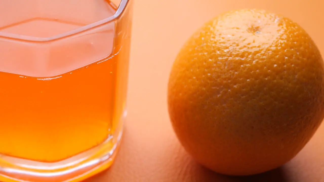 Orange juice in glass and fruits in a bowl on table 