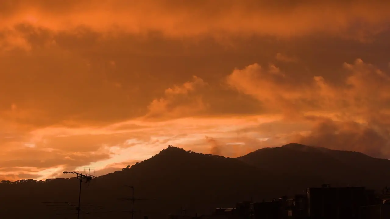 View of distant mountains in an orange sunset while in the sky the clouds move slowly