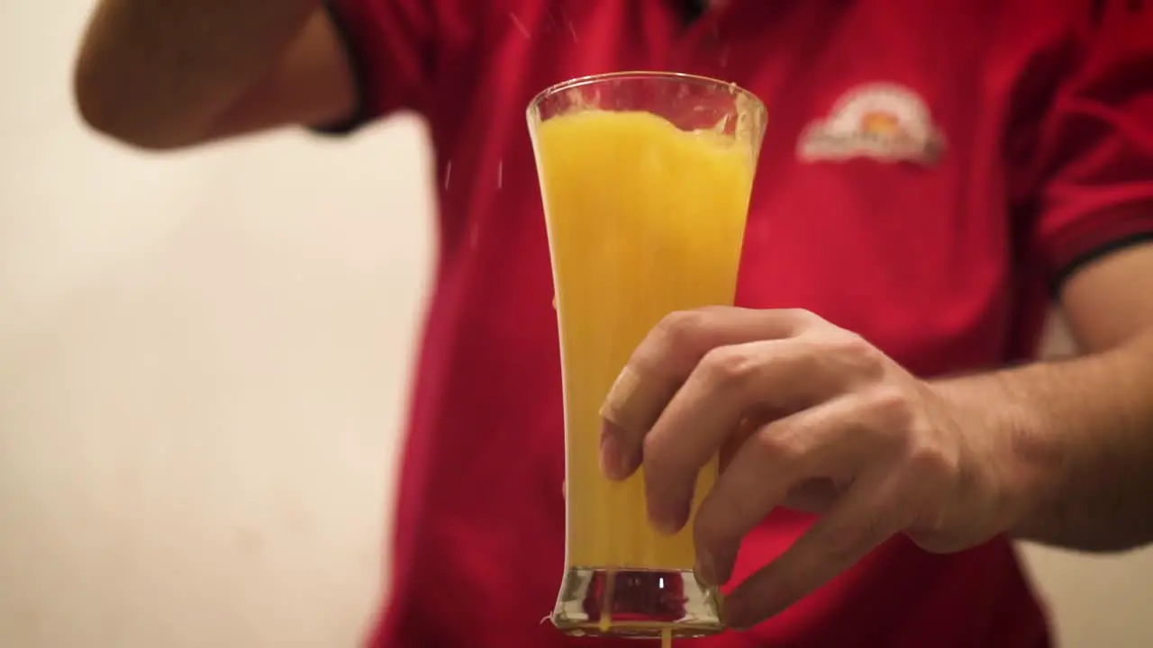 Slow Motion Of Man Dropping Ice Into A Glass Of Orange Juice