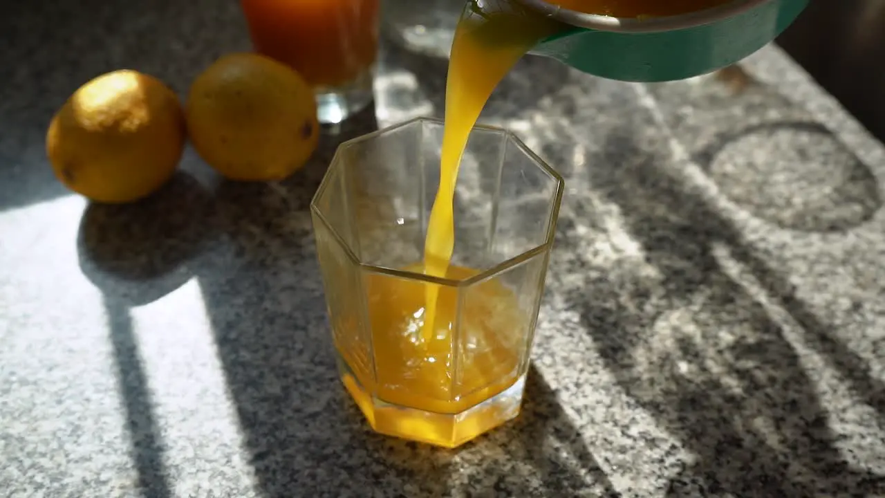 Pouring Fresh Squeezed Orange Juice Into The Empty Clear Glass static low angle shot