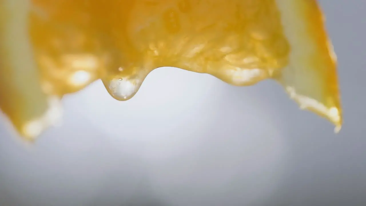 Macro shot squeezing orange slice juice drops falling in Slow motion