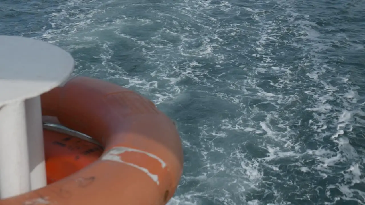 Boat creates turbulent wake stern of vessel with orange life bouy