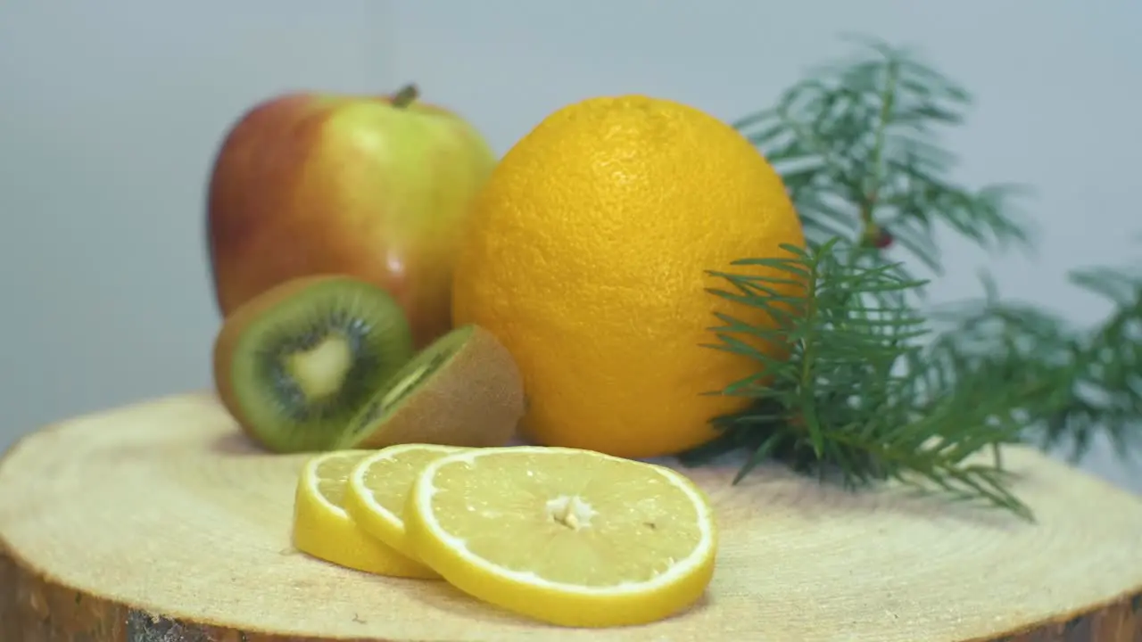 Close up video of camera zooming to the fruits orange apple kiwi and lemon on wooden desk changing focus from lemon to kiwi and apple