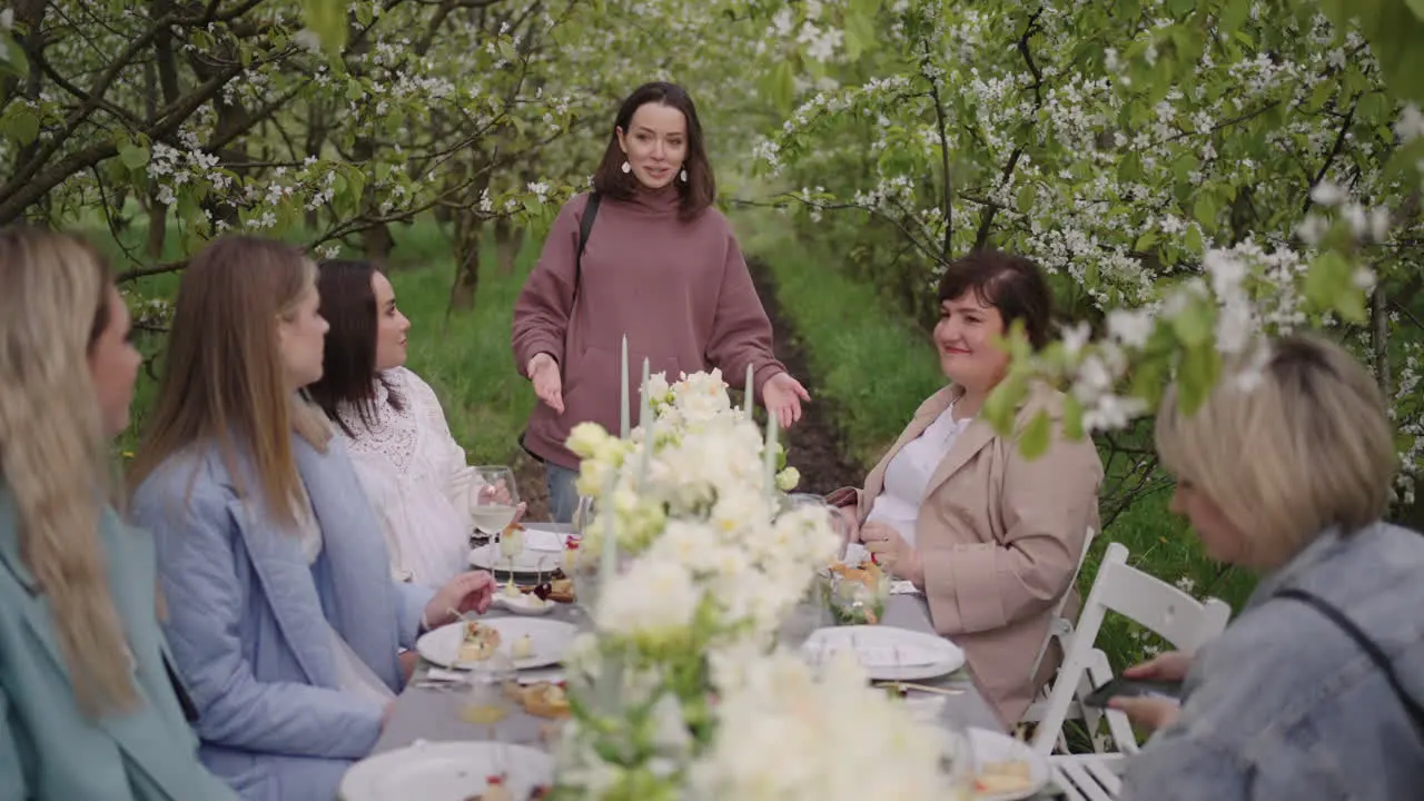 hen party in blooming garden in spring day women are sitting at table with flower decoration