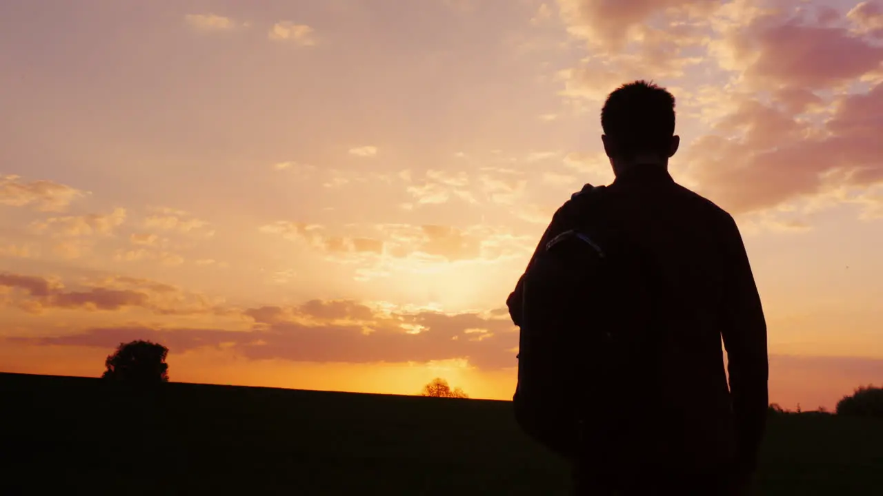 A Teenager With A Backpack Looks Forward To The Sun And The Horizon