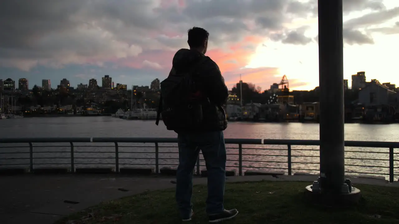 hero shot facing colorful sunset man puts on a winter hat