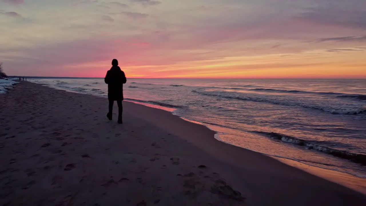 Silhouette of a person on the beach with a colorful sunset at horizon