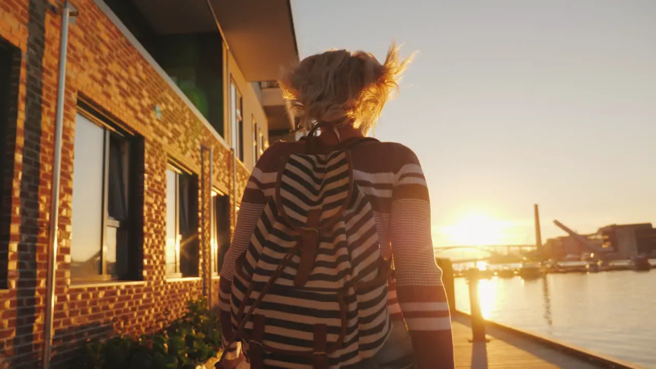 An Active Woman Runs Skipping Along The Embankment The Setting Sun Is Reflected In The Windows Of Th