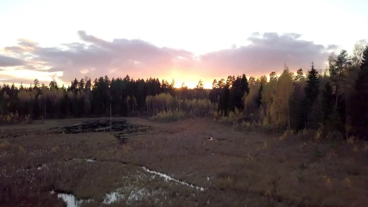 Low aerial shot over the pond towards the sunset in rural area of Latvia Europe