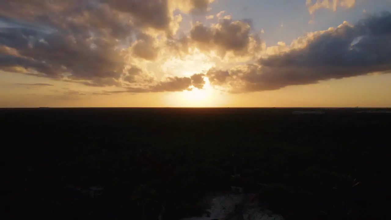 Aerial view of a dramatic sunset sky with a cinematic reveal of the beach on the Caribbean sea in Gitano Tulum